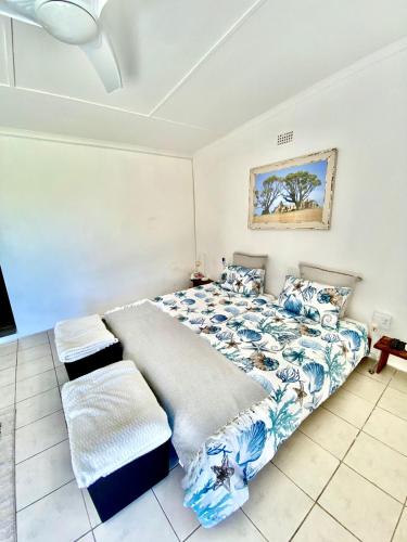 a bedroom with a large bed with blue and white sheets at Sunset Bed and Breakfast in Coffee Bay