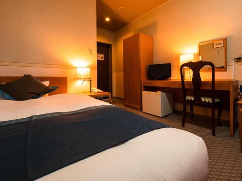 a hotel room with a bed and a desk with a television at Hotel Area One Ise Inter in Ise