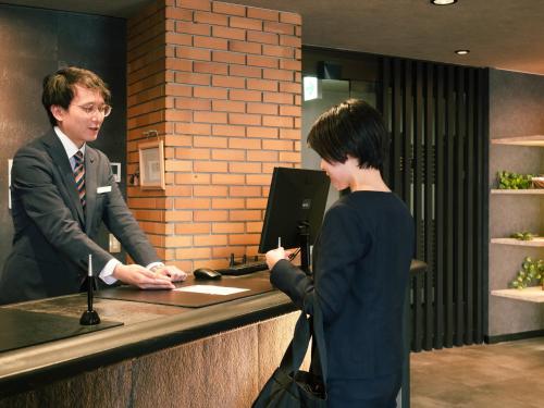 a man and a woman standing at a cash register at Hotel Area One Ise Inter in Ise