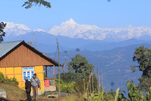 Ein paar Leute stehen vor einem gelben Haus. in der Unterkunft Vamoose Heaven Valley in Pedong