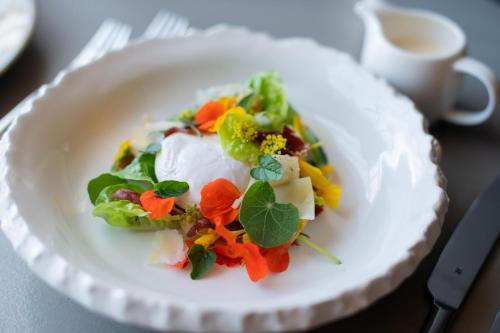 a white plate with a salad on a table at Brahman Hills - Gardens, Hotel & Cottages in Nottingham Road