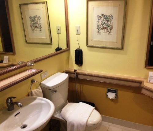 y baño con aseo, lavabo y teléfono. en Waterfront Insular Hotel Davao en Davao