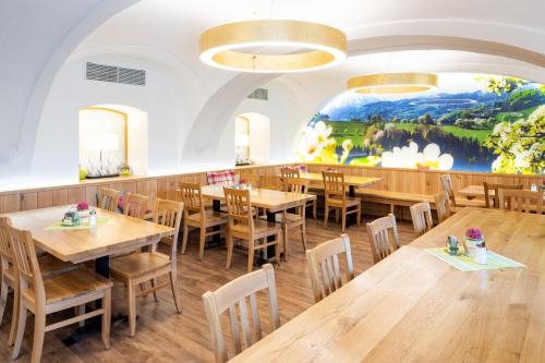 a restaurant with wooden tables and chairs and a painting on the wall at Perbersdorfer Heuriger in Neuhofen an der Ybbs
