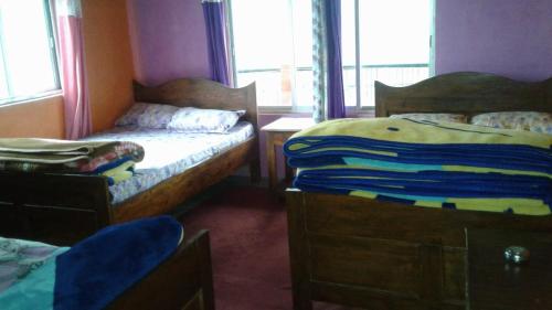 a bedroom with two beds and a table and windows at Vamoose Heema Homestay in Ghum