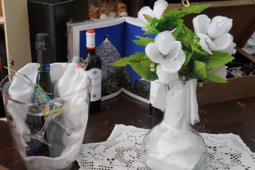 un vaso con fiori e bottiglie di vino su un tavolo di monolocale "le sciabiche" a Brindisi