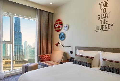 a bedroom with a large bed and a large window at Rove Downtown in Dubai