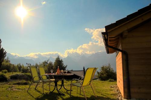 a table and chairs sitting on a lawn with the sun at Chalet Mon Sousou in Nendaz