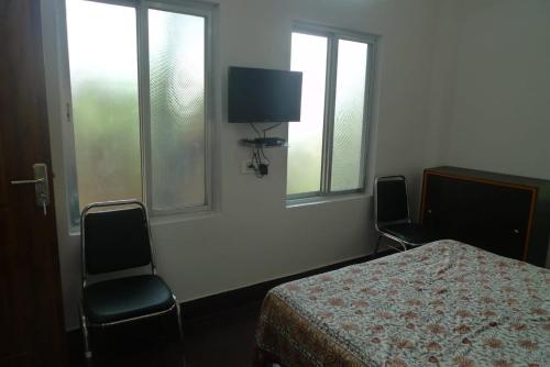 a bedroom with a bed and two chairs and windows at Hilltop Lodge in Nunmāti