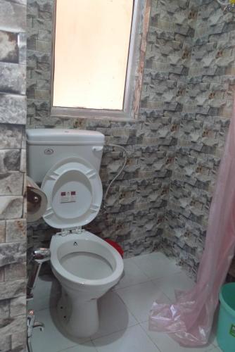 a bathroom with a white toilet with a window at Hilltop Lodge in Nunmāti