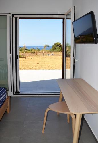 a room with a table and a large window at Splendida Villa NATURE-APPARTAMENTO MELOGRANO a SCOPELLO-ZINGARO vista sul mare in Scopello