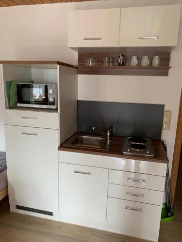 a white kitchen with a sink and a microwave at Gästehaus Brigitte in Garmisch-Partenkirchen