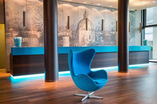 a blue chair in a room with a wall at Motel One Wien-Hauptbahnhof in Vienna