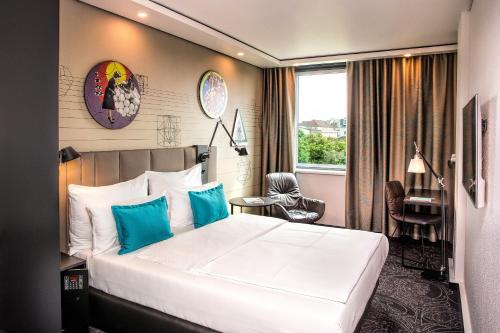 a hotel room with a bed and a desk and a window at Motel One Wien Westbahnhof in Vienna
