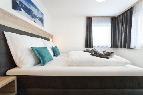 a bedroom with a bed with white and blue pillows at Apart Alina in Schwendau
