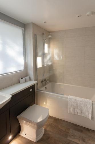 a bathroom with a toilet and a tub and a sink at Cliff House Holiday Cottages in Ebberston