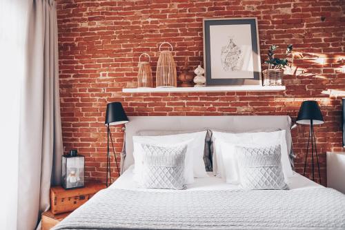 a bedroom with a white bed with a brick wall at Hapsal Dietrich apartemendid in Haapsalu
