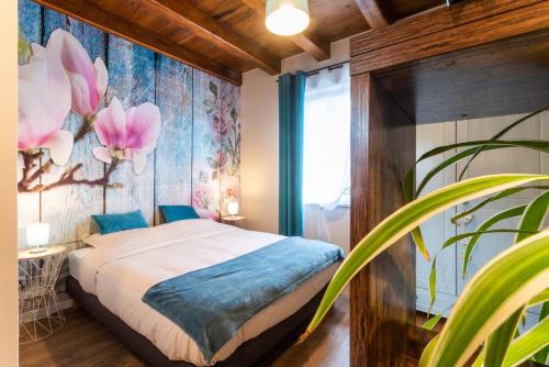 1 dormitorio con 1 cama con un mural de flores en la pared en Gîtes Au fil des saisons proximité EUROPA PARK, en Diebolsheim