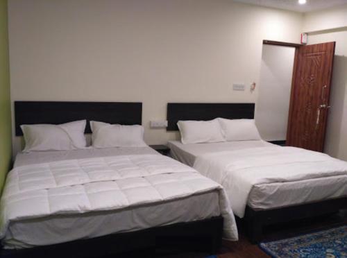 two beds in a bedroom with white sheets at The Meadows in Kodaikānāl
