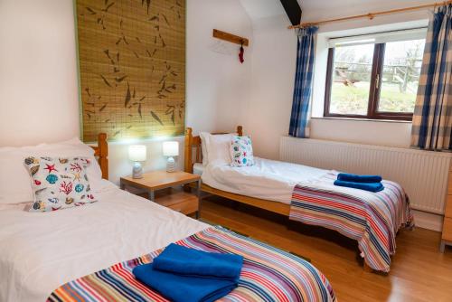 a room with two beds and a window at Polrunny Farm Elderberry Cottage with sea view in Boscastle