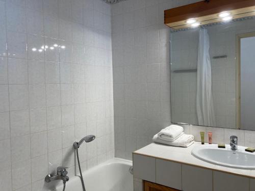 a bathroom with a tub and a sink and a mirror at Résidence hôtelière Le Provençal à Giens - Bord de mer in Hyères