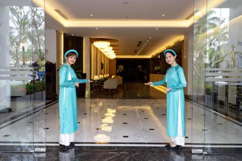 a woman standing in a glass case in a lobby at White Lotus Hue Hotel in Hue