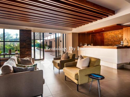 バリートにあるLuxurious 2 Bed Zimbali Suites Sea Viewのリビングルーム(ソファ、椅子付)、バー