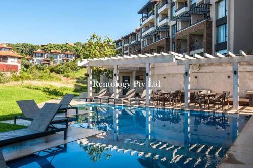 a swimming pool with chairs and a building at Beautiful 1 Bed Zimbali Suites with Garden in Ballito