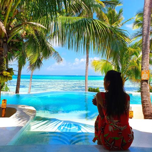 a woman sitting next to a swimming pool overlooking the ocean at Boutique Hotel Matlai in Michamvi