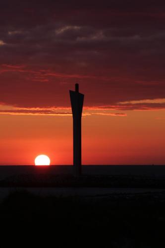 a silhouette of a structure in front of a sunset at Harbourskitchenhouse@sea in Bredene