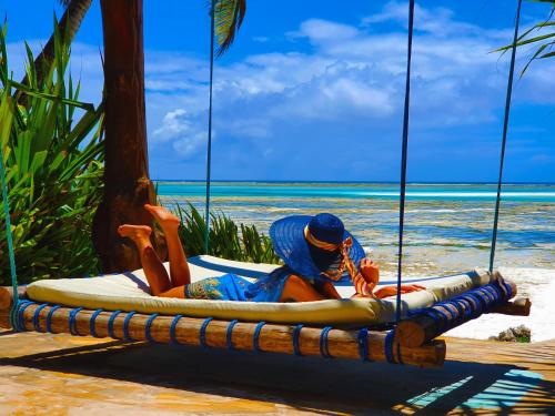 a woman laying on a surfboard on a beach at Boutique Hotel Matlai in Michamvi