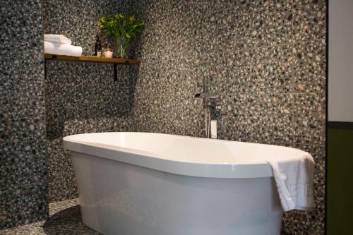 a white bath tub in a bathroom with mosaic tiles at Mason's Arms in Bowland Bridge