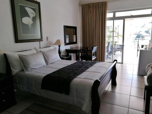 a bedroom with a bed and a table and a balcony at Sunset Boulevard Riverlodge in Paarl