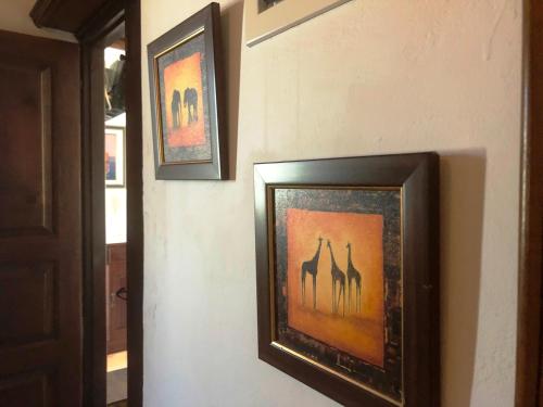 two framed pictures of giraffes on a wall at Machi's House in Plaka Milou