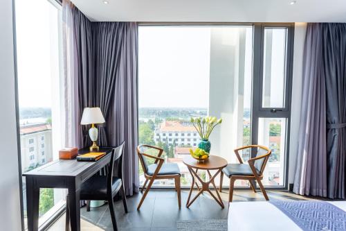 a room with a desk and chairs and a window at White Lotus Hue Hotel in Hue