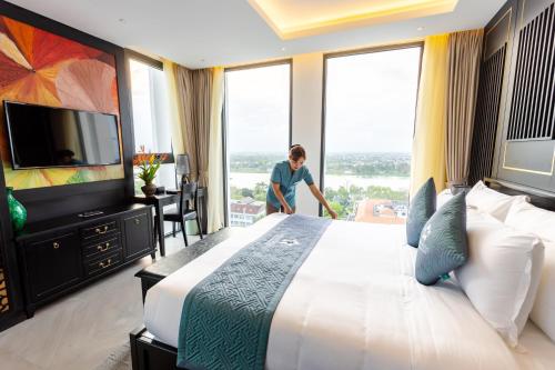 a woman in a hotel room with a large bed at White Lotus Hue Hotel in Hue
