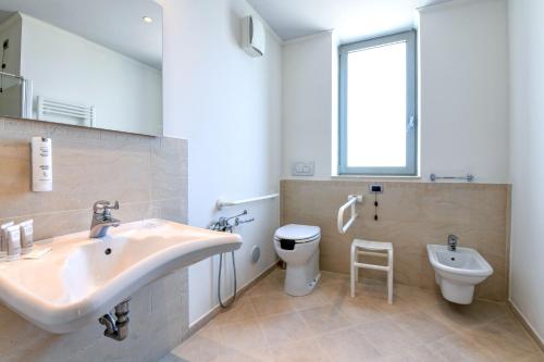 a bathroom with a sink and a toilet and a window at Hotel Rivus in Peschiera del Garda