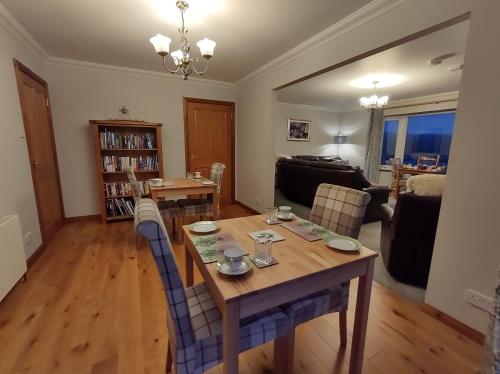 a living room with a wooden table and chairs at B&B Ronan House in Edinbain