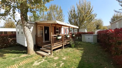 eine kleine Hütte mit einer Veranda und einem Baum in der Unterkunft Mobil Home à Condrieu in Condrieu