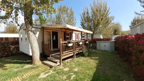 une petite cabane avec une véranda et un arbre dans l'établissement Mobil Home à Condrieu, à Condrieu