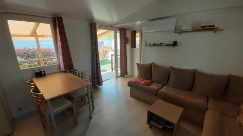 ein Wohnzimmer mit einem Sofa und einem Tisch in der Unterkunft Mobil Home à Condrieu in Condrieu