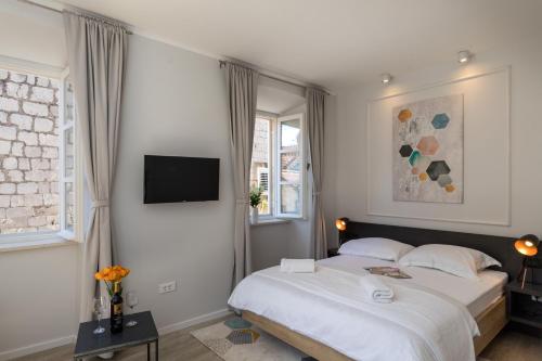 1 dormitorio con 1 cama y TV en la pared en Apartments Urbis, en Dubrovnik