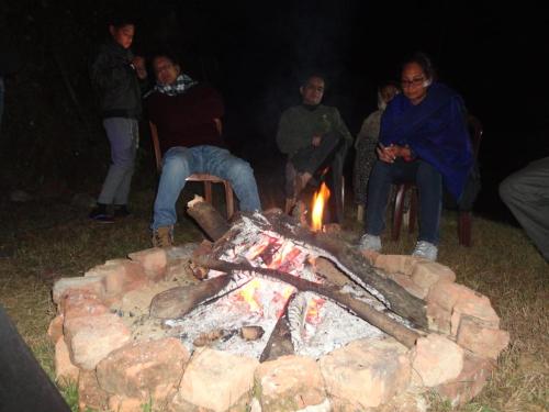 a group of people sitting around a camp fire at Vamoose Himalayan Viewpoint in Ravangla