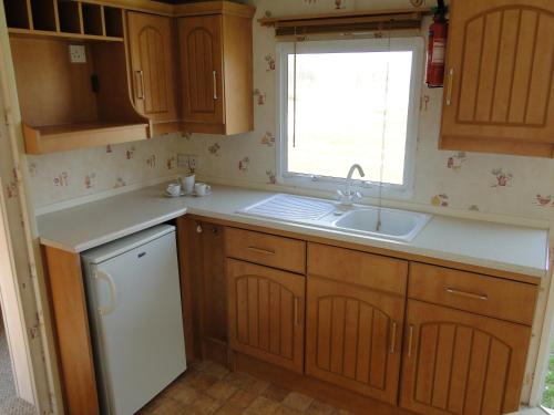a kitchen with wooden cabinets and a sink and a window at Lary Camping Homes - Domki Gorzewo in Gostynin