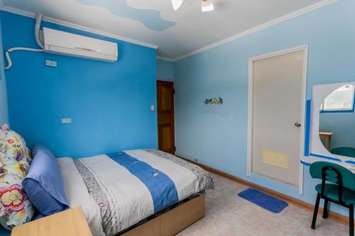 a blue bedroom with a bed and a chair at 幸福月光民宿 Evening Sun in Green Island