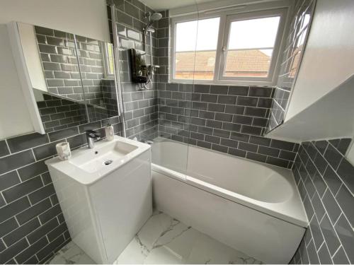 y baño con bañera blanca, lavamanos y bañera tubermott. en Charming Town Centre Character Cottage With Parking en Stowmarket