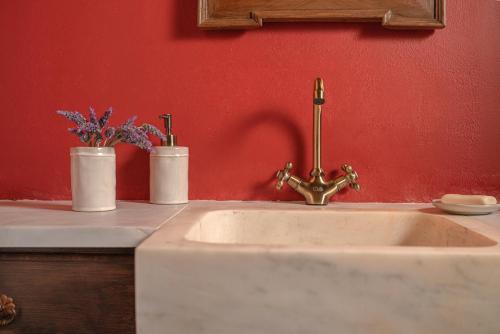a bathroom sink with two vases on a red wall at The 1813 Painter's Villa by Neuvel in Galaxidhion