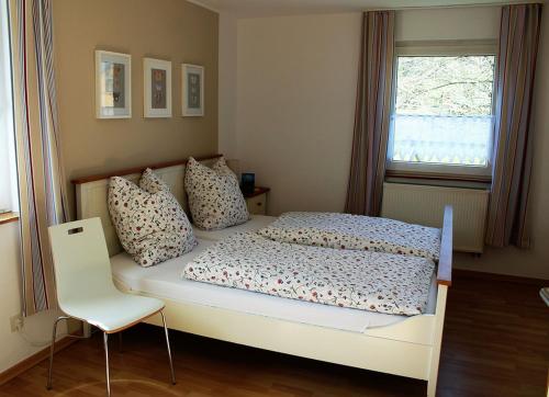 een slaapkamer met een bed, een stoel en een raam bij Ferienwohnung Peitz in Eslohe