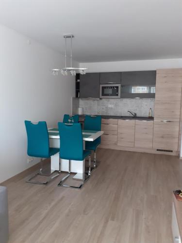 a kitchen with a dining table and blue chairs at Ezüst Apartman in Siófok