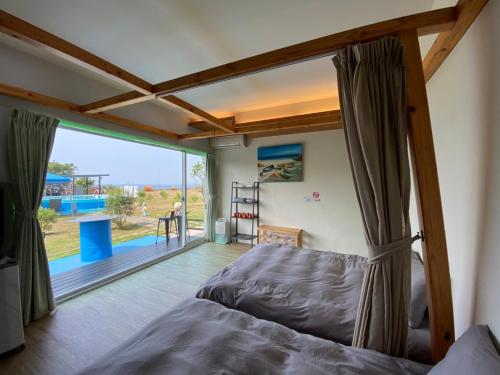 a bedroom with a bed and a large window at Happiness Ocean View B&B in Xiaoliuqiu