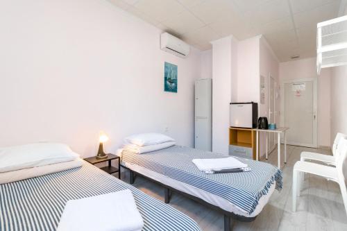 um quarto com duas camas e uma tv nele em Hostal 7A em Torrevieja